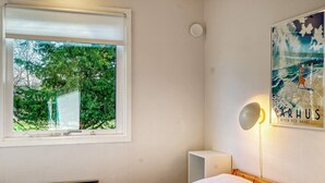 A bedroom with a bed, a window with a view of trees, a wall-mounted lamp, and a framed picture. - 4 Star Holiday Home in Dannemare (Dannemare)
