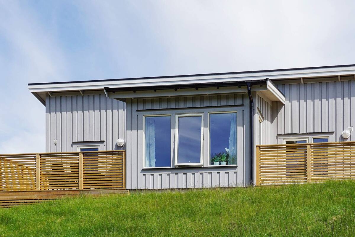 A modern building with a flat roof, large windows, and a wooden fence.