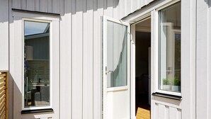 Un bâtiment moderne doté d’une terrasse en bois, d’une porte-fenêtre coulissante et d’une fenêtre.