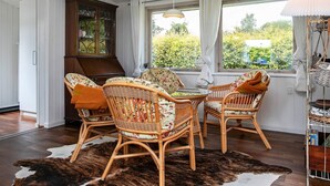 A room with wicker furniture, a glass-top table, a cowhide rug, and a view of greenery outside. - Holiday Home in Fjällbacka (Faxe Ladeplads)