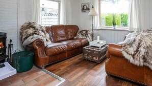 A cozy room with a brown leather sofa, a wooden coffee table, and a fireplace. - Holiday Home in Fjällbacka (Faxe Ladeplads)