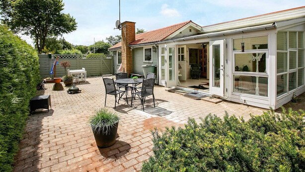 A patio with a brick floor, a table with chairs, and a potted plant. - Holiday Home in Fjällbacka (Faxe Ladeplads)