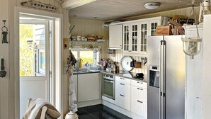 A kitchen with white cabinets, a stainless steel refrigerator, and a window providing natural light. - 7 Person Holiday Home in Jelsa (Suldal)