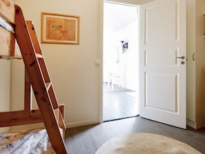 Une pièce avec une échelle en bois, une porte blanche et un tableau encadré accroché au mur.