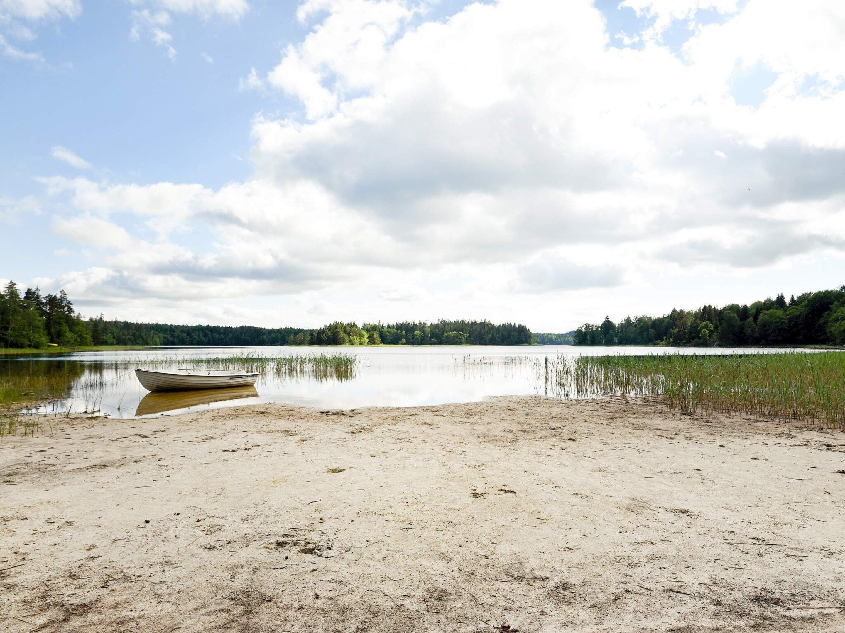 Un lago con un bote en la orilla, rodeado de árboles y un cielo nublado.