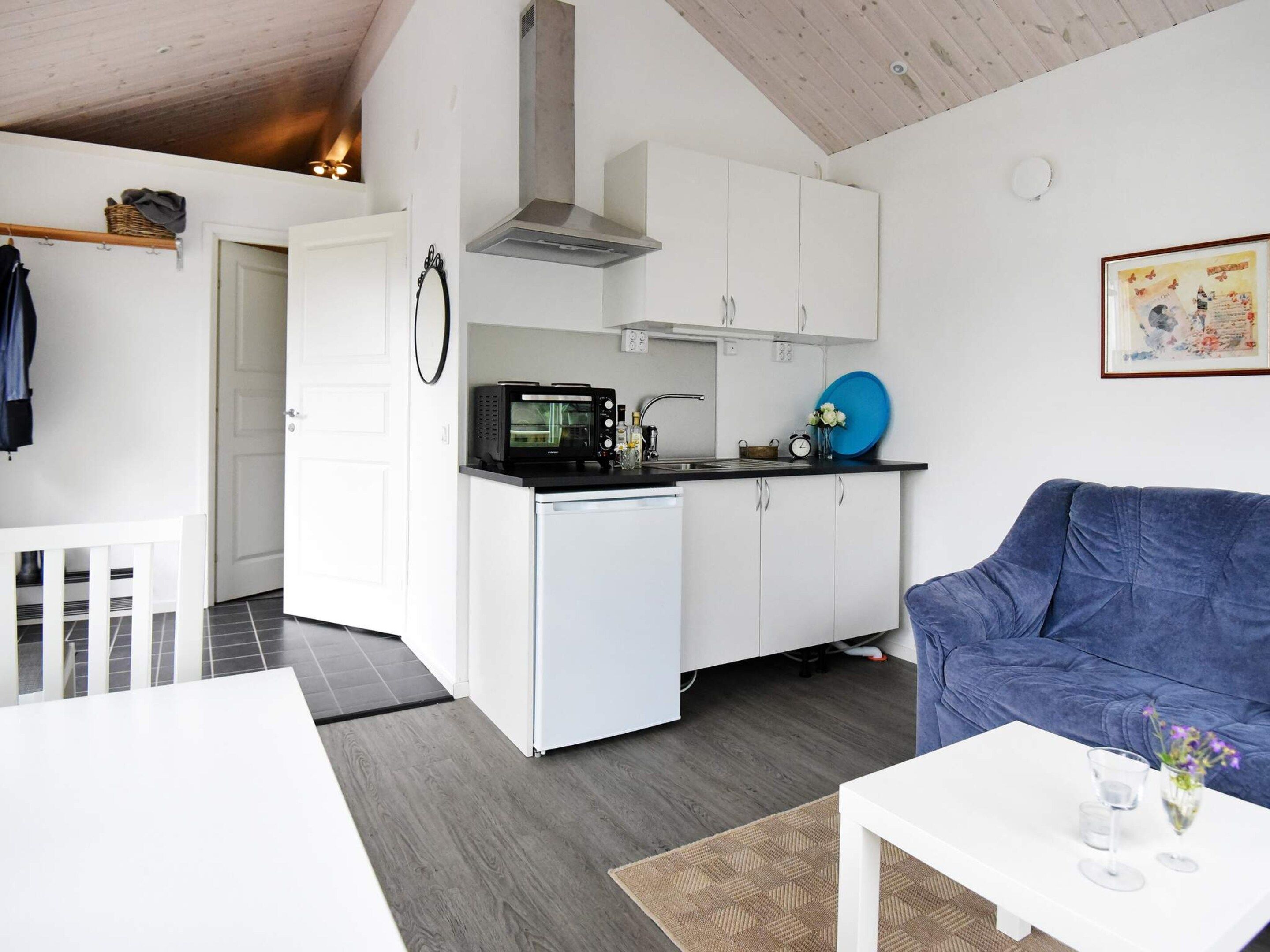 A compact living space with a kitchenette, a dining area, and a seating area with a blue sofa.