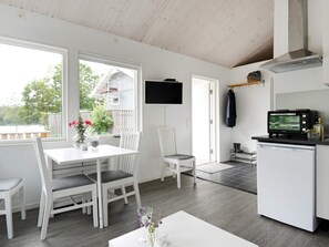 Una cocina moderna con microondas integrado, un comedor con sillas blancas y un amplio ventanal con vistas a una terraza.