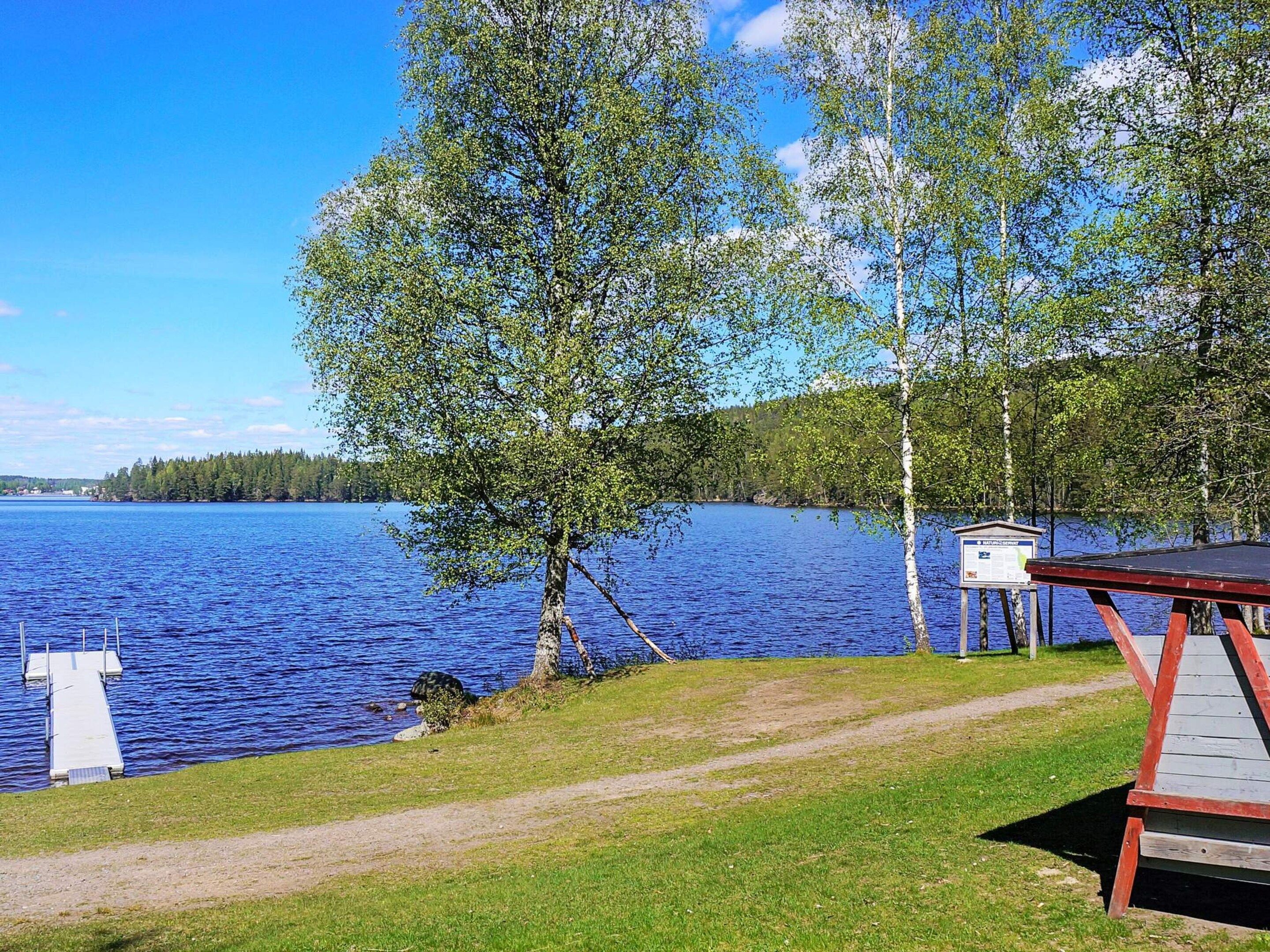 A lakeside view with a dock, a covered seating area, and a signboard.