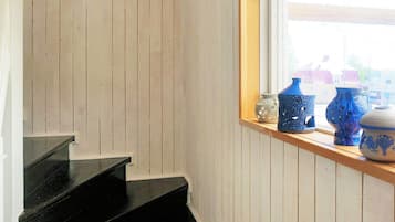 A staircase with white paneling and a window with decorative vases.