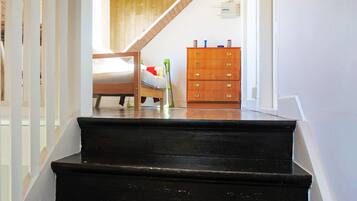 A staircase leading to a bedroom with a bed, a dresser, and a wooden ceiling.