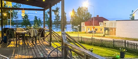 A wooden deck with outdoor seating, a metal chair, and a view of a building across a street.