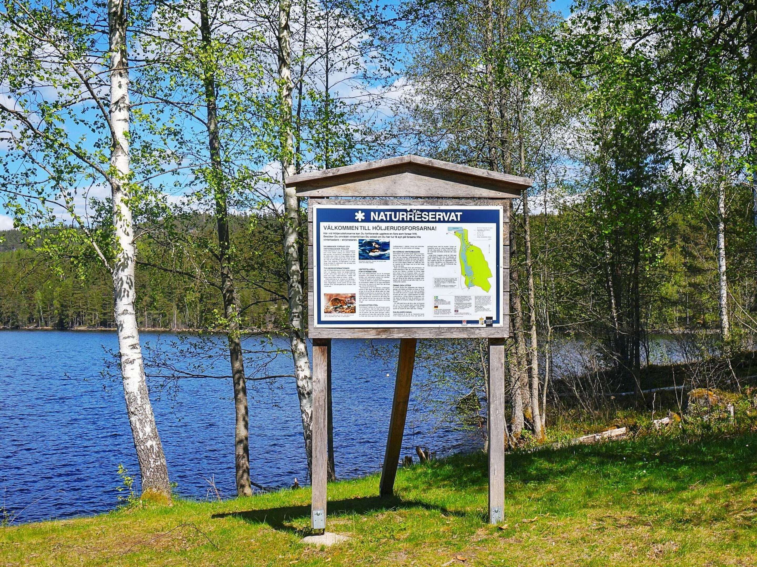 A signboard with information about a nature reserve by a lake.