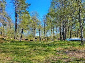 A park with a swing set and a canoe in the background. - Idyllic Lakeside Retreat in Munkedal-by Traum (Färgelanda)