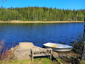 A calm lake with a wooden bench and a small boat by the shore. - 4 Person Holiday Home in Fargelanda (Färgelanda)