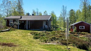 Une maison à deux étages avec un porche couvert et un petit abri attenant.