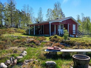 A cabin with a porch, surrounded by a natural landscape with rocks and vegetation. - 4 Person Holiday Home in Fargelanda (Färgelanda)