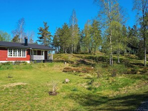 A red house with a porch, surrounded by a grassy area and trees. - 4 Person Holiday Home in Fargelanda (Färgelanda)