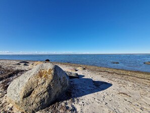 A rocky shoreline with clear blue water and distant land. - 5 Person Holiday Home in Grenaa (Grenaa)