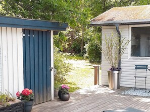 A wooden deck with a shed, a potted plant, and a bench.