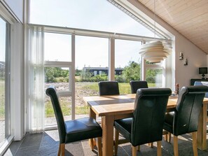 Un comedor con mesa y sillas, ventanas amplias y vistas al exterior.