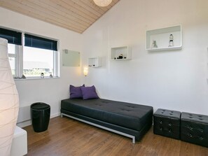 Un dormitorio moderno con una cama, mesitas de noche, una ventana y un estante pequeño con adornos decorativos.
