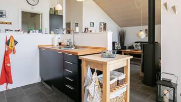 Una cocina moderna con una isla de madera, armarios negros y una lámpara colgante.