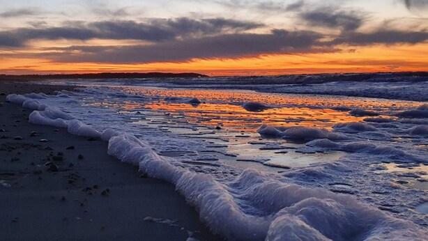 Ein Strand mit Wellen bei Sonnenuntergang.