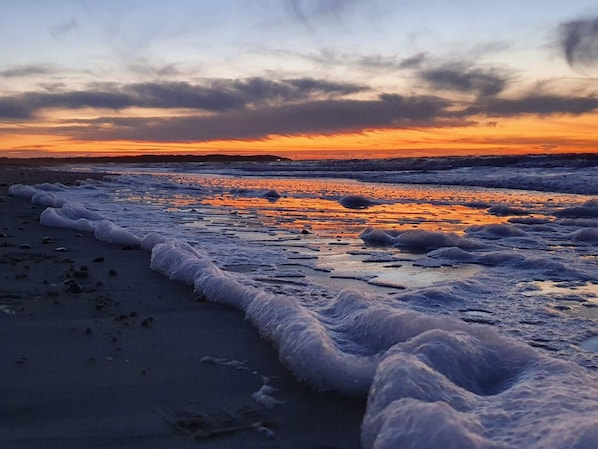 A beach with waves at sunset.