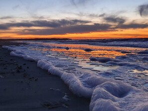 Una playa con olas al atardecer.