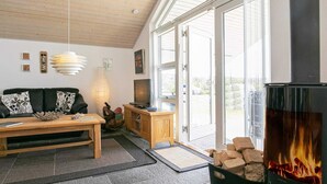 Ein gemütliches Wohnzimmer mit Kamin, einer Couch, einem Couchtisch und einem Fernseher.