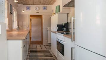 A compact kitchen with a wooden ceiling, a built-in oven, a coffee maker, and a radiator.
