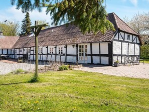 Um edifício tradicional em estilo de enxaimel com telhado de telhas, pátio pavimentado e mesas ao ar livre.