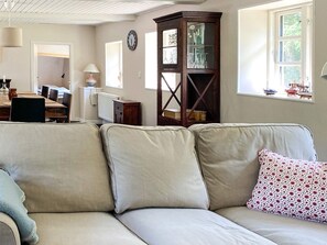 Ein Wohnzimmer mit einer Couch, einer Holzkommode und einem Essbereich im Hintergrund.