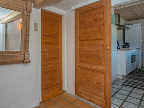 Corredor com portas de madeira e área de cozinha com fogão e pia.