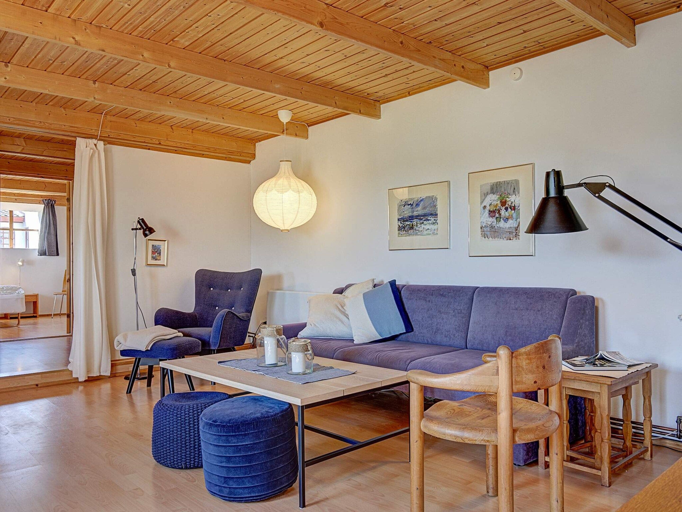 A modern living room with a wooden ceiling, a sofa, a coffee table, and a chair.