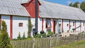 A white building with red accents, a chimney, and a wooden fence.