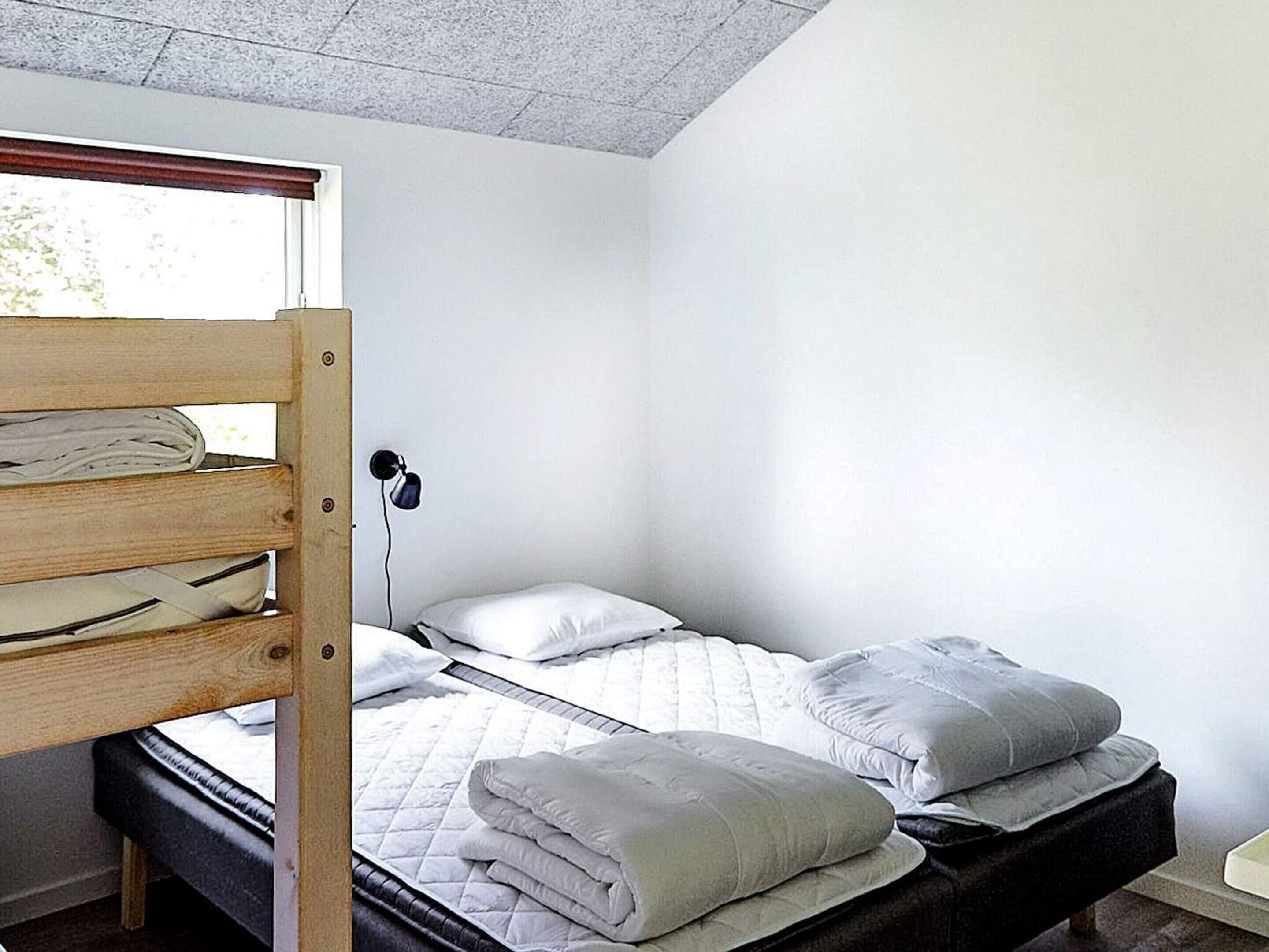 Ein Zimmer mit einem Etagenbett, einem Nachttisch, einer Lampe und einem Fenster.