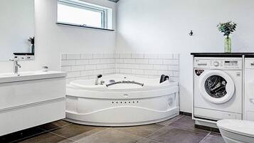 Un baño moderno con una bañera independiente, lavadora integrada y un inodoro.