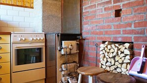 A kitchen with a Bosch oven, a brick wall, a fireplace with logs, and wooden stools. - 4 Person Holiday Home in Ucklum (Ucklum)