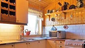 A kitchen with wooden cabinets, a sink, a microwave, and an oven. - 4 Person Holiday Home in Ucklum (Ucklum)
