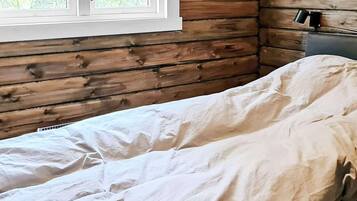 Een houten kamer met een bed, een raam en een nachtkastje.