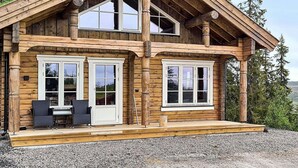 A two-story log cabin with a covered porch and a dining area. - 8 Person Holiday Home in Veggli (Rollag)