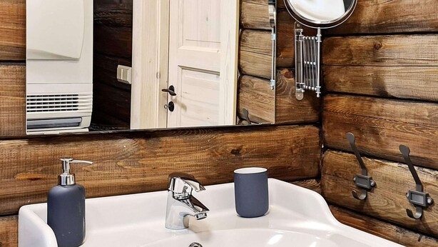 A bathroom with a white sink, two soap dispensers, a mirror, and wooden paneling. - 8 Person Holiday Home in Veggli (Rollag)