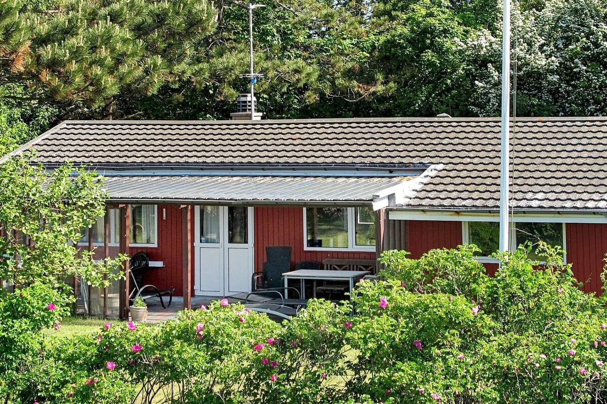 A small, single-story building with a tiled roof, a front porch, and a dining area.