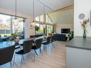 A modern interior with a dining area, seating, and a TV. - Holiday Home in Juelsminde (Juelsminde)