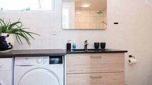 A modern bathroom with a washing machine, a sink, a mirror, and a small plant. - 6 Person Holiday Home in Glesborg (Glesborg)