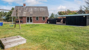 A brick building with a metal roof, a swing set, and a covered outdoor area.