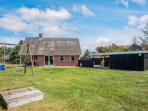 A brick building with a metal roof, a swing set, and a covered outdoor area.