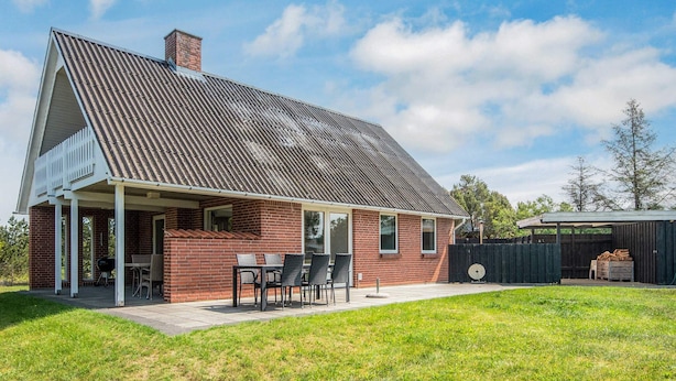 A single-story house with a covered patio, a brick exterior, and a metal roof.