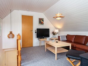 A cozy room with a television, a wooden coffee table, a brown leather sofa, and a ceiling fan. - 6 Person Holiday Home in Glesborg (Glesborg)